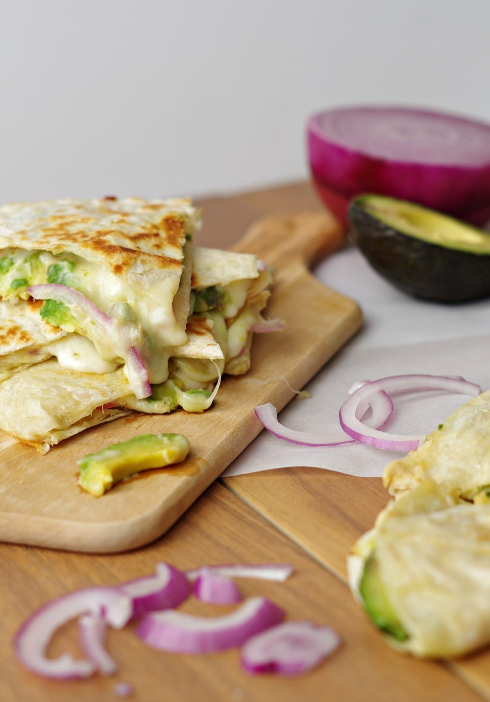 close up of dripping cheese Hummus, Avocado and Cheese Quesadillas on wood plank