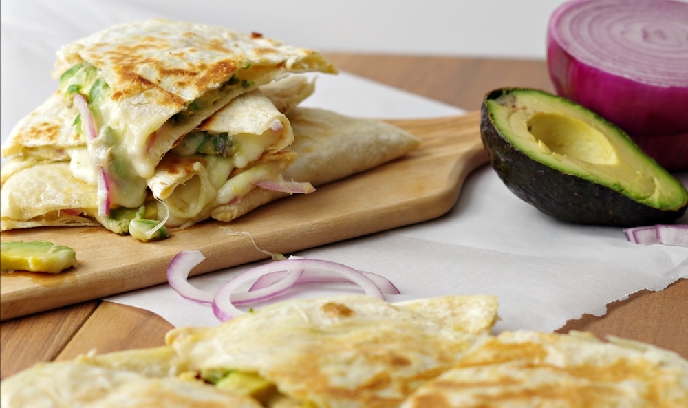 Hummus, Avocado and Cheese Quesadillas on wood plank close up horizontal