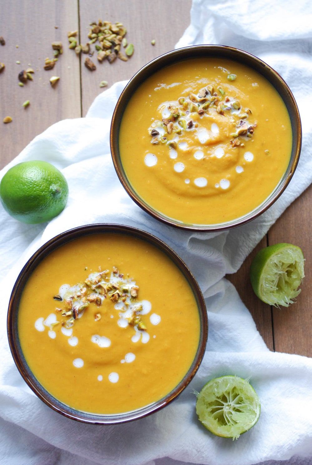 two bowls of Thai Pumpkin and Sweet Potato Soup with squeezed limes