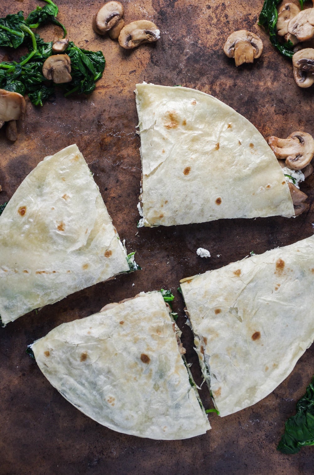 Quartered Mushroom Quesadilla with scattered Mushrooms and Spinach 