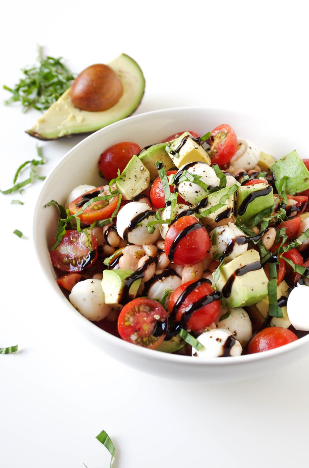 close up image of Caprese Salad with Avocado and Balsamic Glaze in white bowl