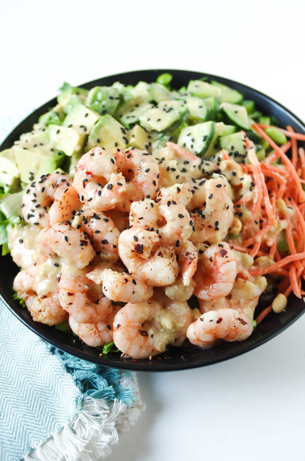 Cooked shrimp, cubes of avocado, cucumber, shredded carrots, on top of mixed greens and drizzled with homemade miso salad dressing.