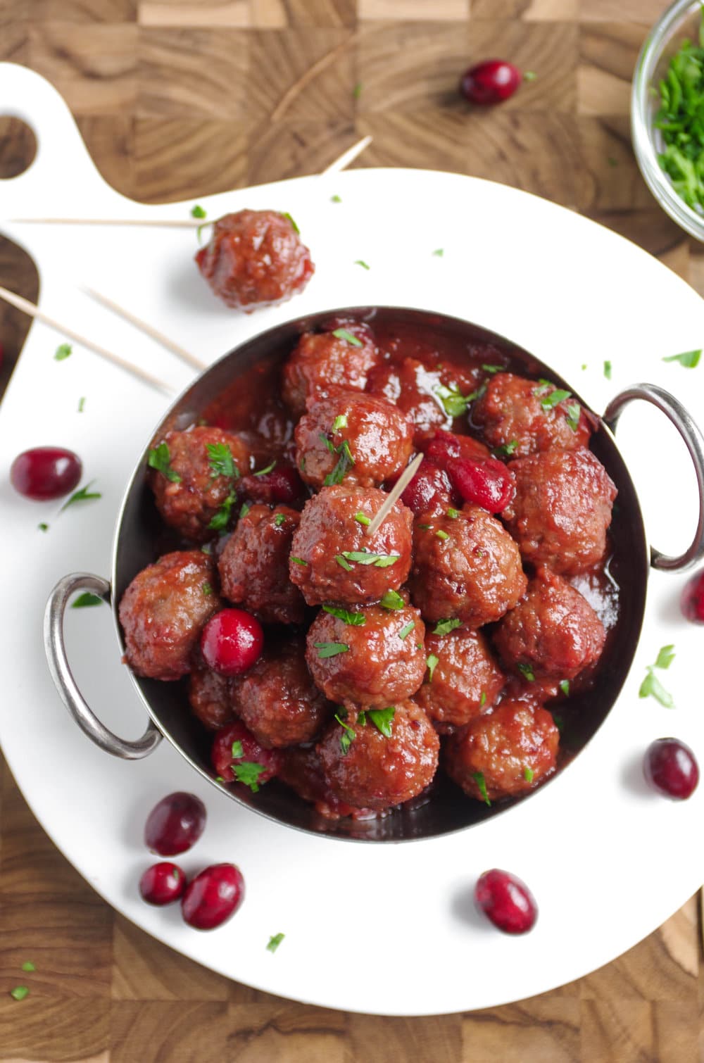 Overhead image of a shallow bowl filled with cranberry meatballs garnished with chopped parsley.