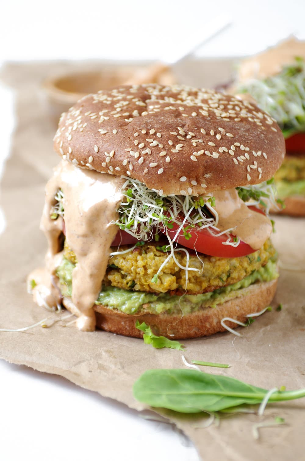 Easy Cauliflower Veggie Burgers with Avocado and Chipotle Mayo dripping out sides on brown paper