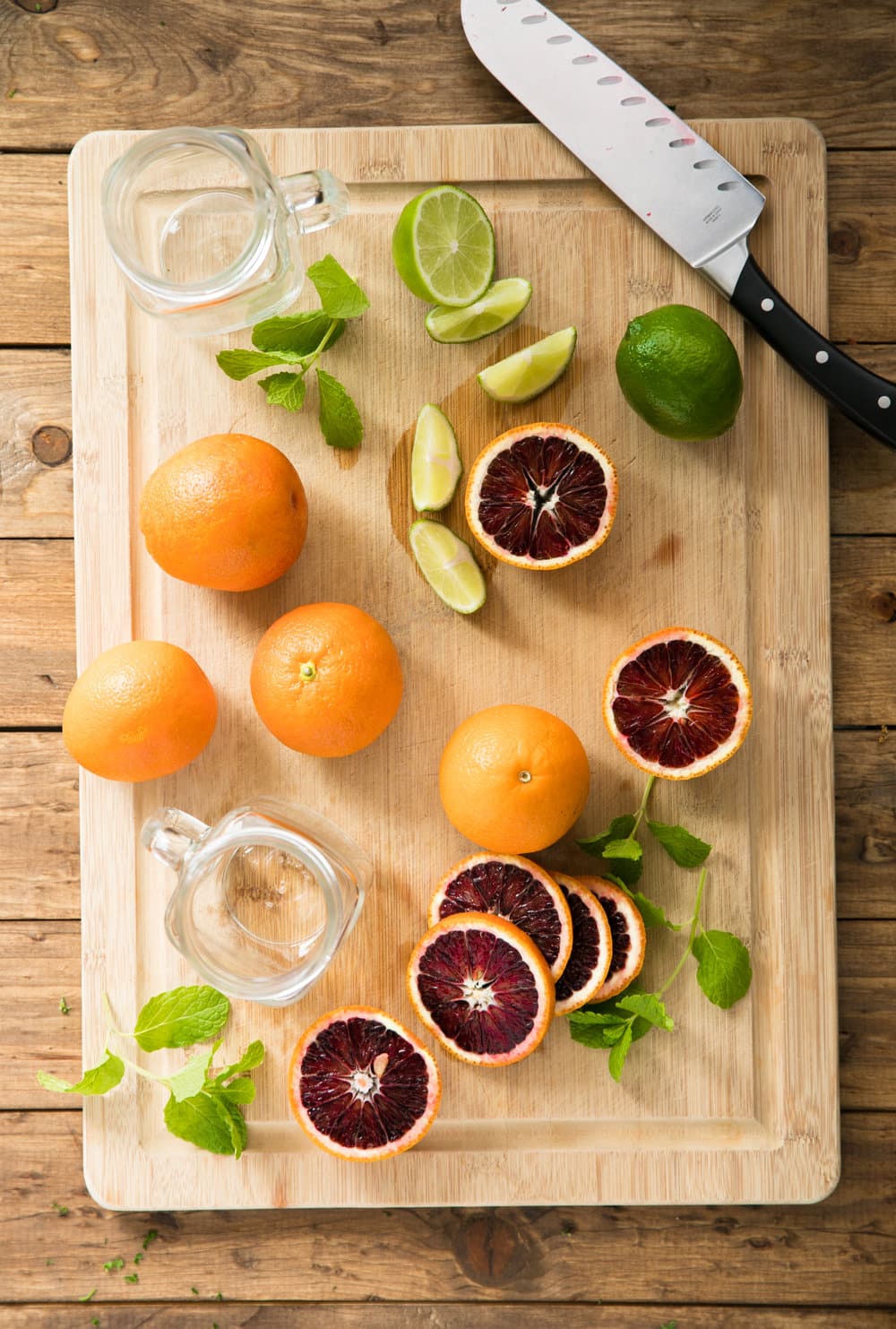 blood oranges, limes, mint on cutting board with knife and mason jars for  Kombucha Mocktail